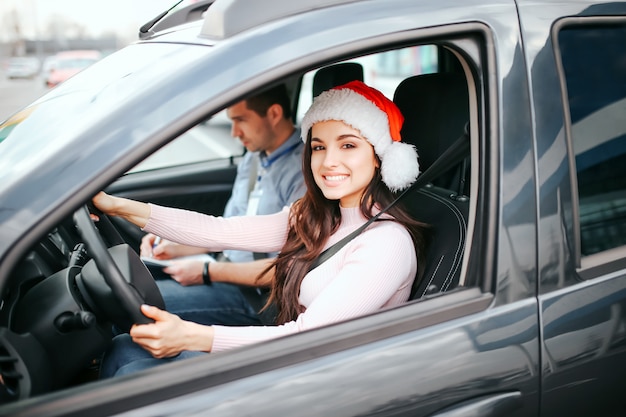 Young beautiful cheerful woman sit on driver's place in car. 