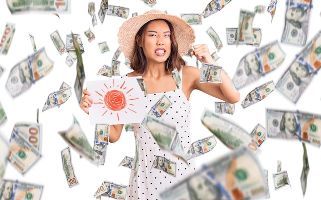 Young beautiful chinese girl wearing summer hat holding sun draw annoyed and frustrated shouting with anger yelling crazy with anger and hand raised