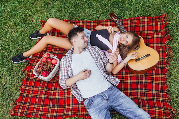 Young beautiful couple lie on the blanket carpet and looking each other in the blanket carpet and girl looking to the camera.Love