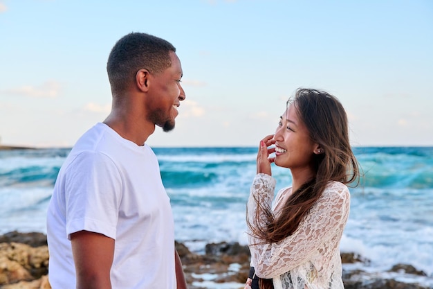 Young beautiful couple looking in the eyes in profile on the seascape