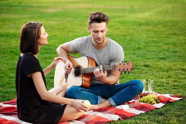 Young beautiful couple smiling resting on picnic in park