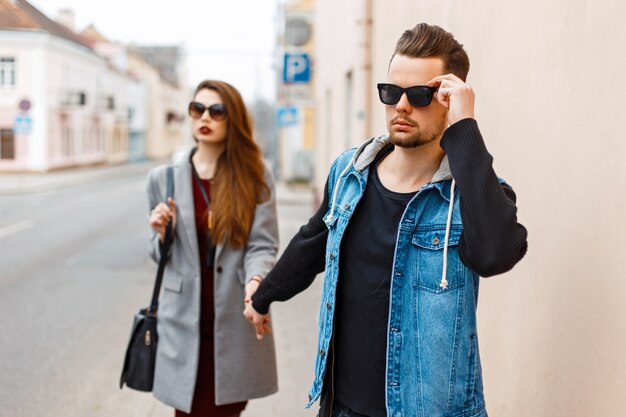 Young beautiful couple in sunglasses goes on the street