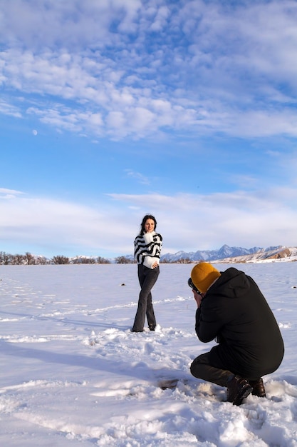 A young beautiful couple of tourists a man and a woman take photographs as a souvenir in the winter landscape