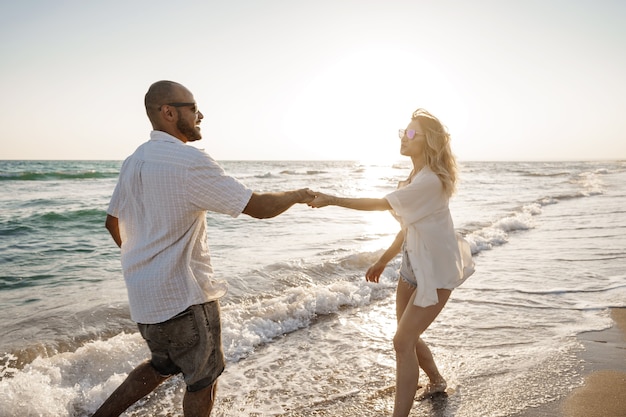 Young beautiful couple walking on beach near sea