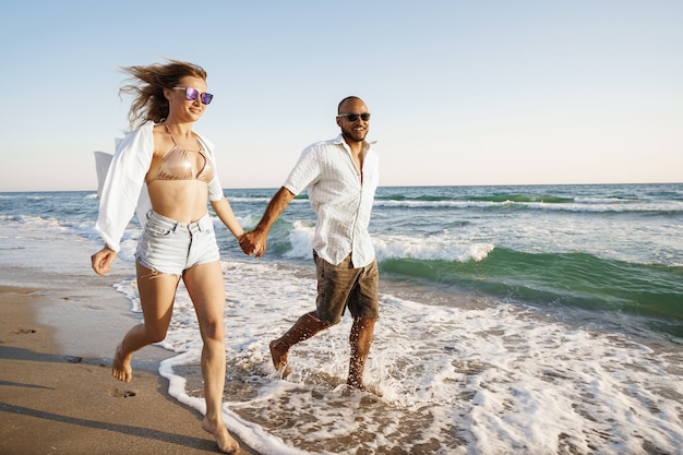 Young beautiful couple walking on beach near sea