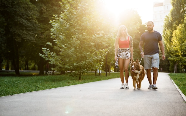 Young beautiful couple walking the dog in the summer park