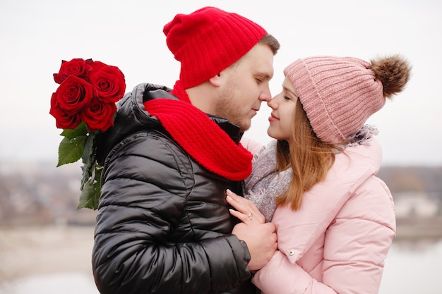 Young beautiful couple with red roses outdoors