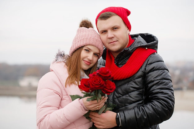 Young beautiful couple with red roses outdoors