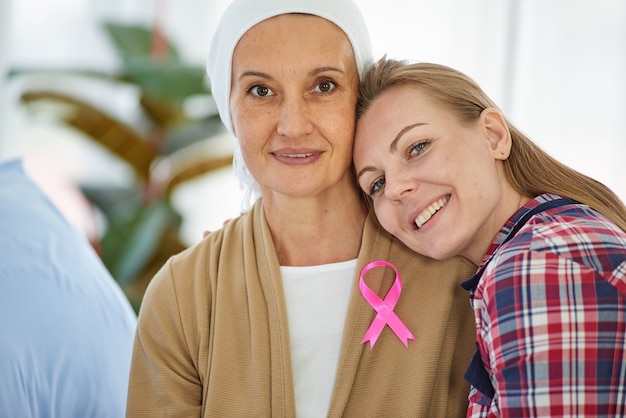 Young beautiful daughter sit beside mother who fight to the cancer for support her on hospital bed