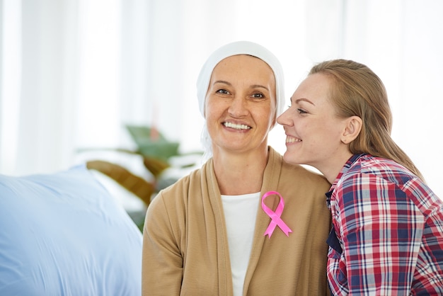 Young beautiful daughter sit beside mother who fight to the cancer for support her on hospital bed