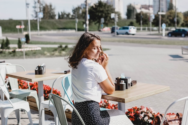 Photo young beautiful european woman sits in the summer on a cafe terrace