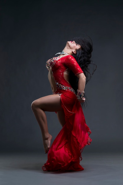 Young beautiful exotic eastern women performs belly dance in ethnic red dress