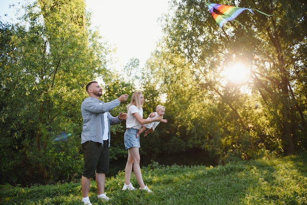 Young beautiful family with a little daughter hug, kiss and walk in nature at sunset. Photo of a family with a small child in nature.