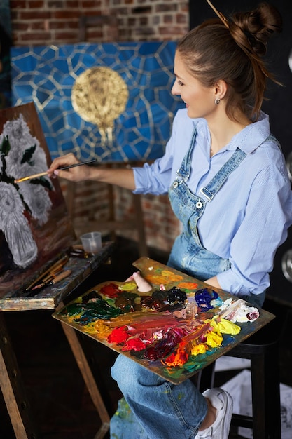 Young beautiful female artist painting still life with sunflower on canvas using oil paintings