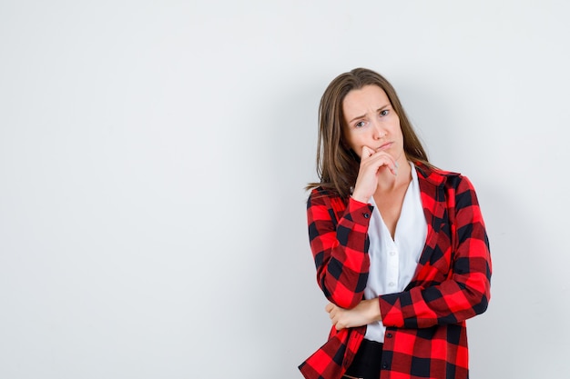 Young beautiful female in casual outfit standing in thinking pose and looking puzzled , front view.