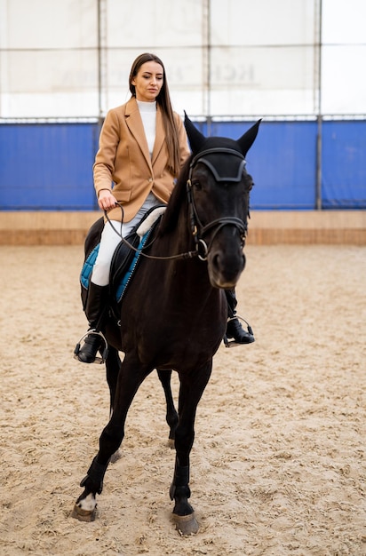 Young beautiful female horse rider Pretty jockey on a horseback