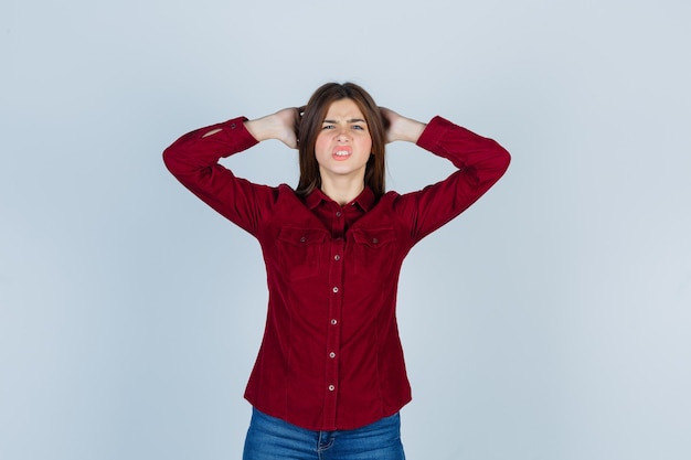 Photo young beautiful female in shirt holding hand behind head and looking troubled