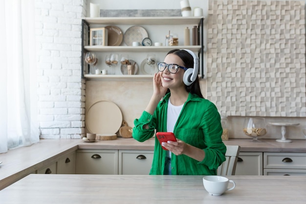 A young beautiful female student is studying in headphones studying at home online from the phone