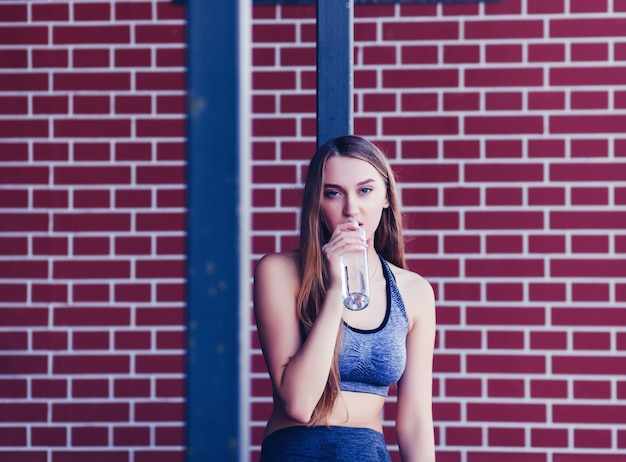 Young beautiful fit woman drinking water