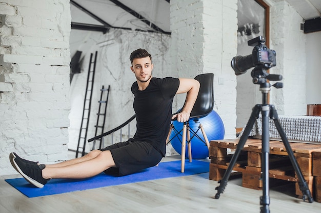 The young, beautiful fitness blogger writes videos for his blog and talks about the tools at work during a training session in a loft-style room