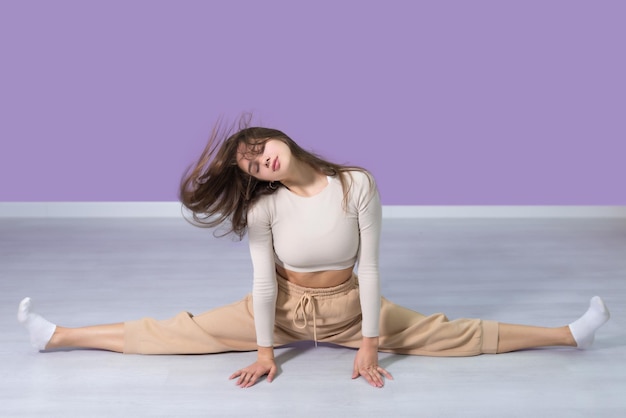 Photo young, beautiful, fitness woman is doing twine. her hair is developing. the girl gives twine in the gym.