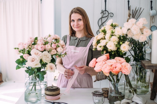 Young beautiful florist in a flower shop