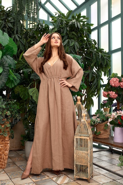 Young beautiful girl in beige dress posing in indoor garden