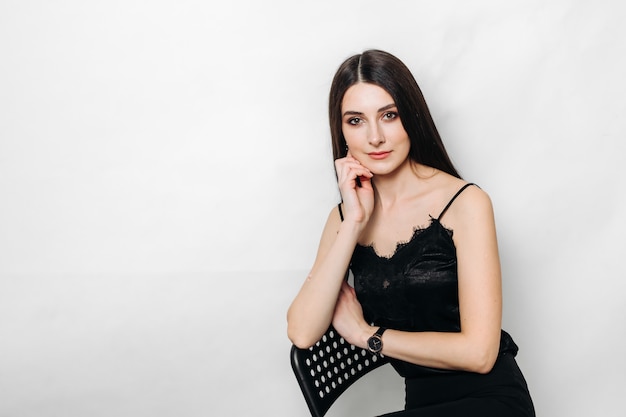 A young beautiful girl in black clothes on a white wall. space for text