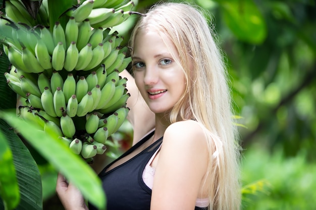 Young beautiful girl blond hair standing by banana tree