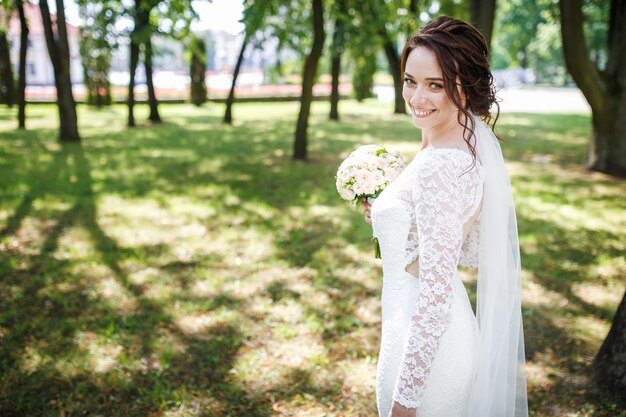 Young beautiful girl bride in a peignoir standing st city park waiting for the groom