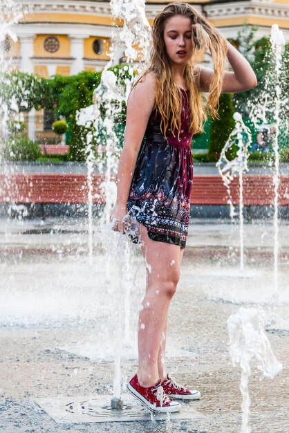 Young beautiful girl dances in a fountain