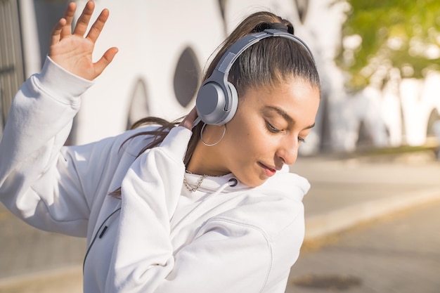 Young beautiful girl dancing happy in the street with headphones