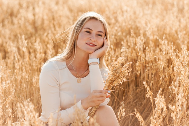 A young beautiful girl in a denim skirt walks through a wheat field on a sunny day