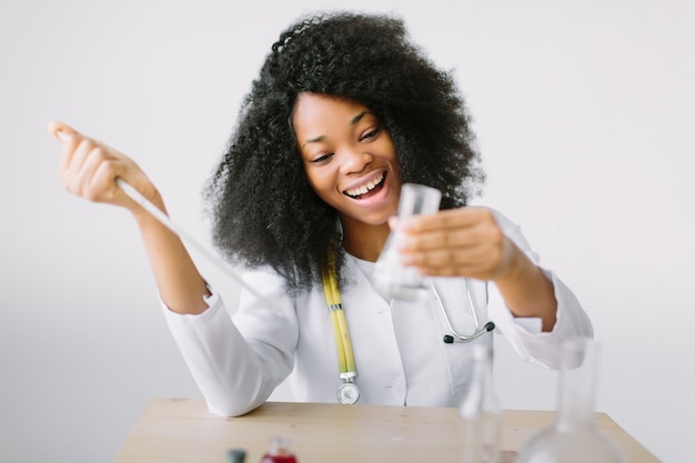 Young beautiful  girl doctor in a white coat with a stethoscope. sitting at a table and Analyzing Sample In Laboratory.laboratory assistant analyzing a sample.