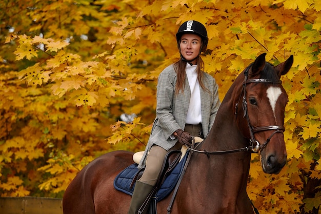 Young beautiful girl in dress riding a horse in the autumn forest