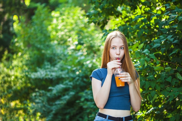 Young beautiful girl drinks freshly squeezed juice on a background.