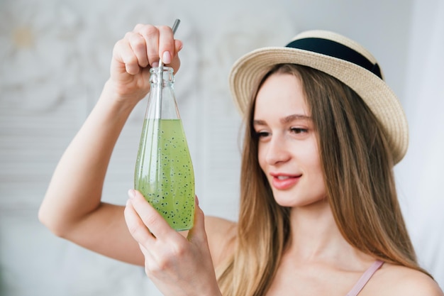 Young beautiful girl drinks a healthy green drink with Basil seeds through a reusable metal tube. The concept of healthy nutrition, environmental friendliness and zero waste. Toning.