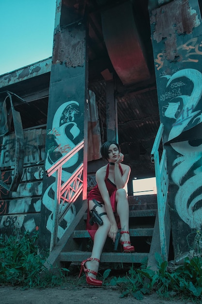 Young beautiful girl in an evening red dress with a gun