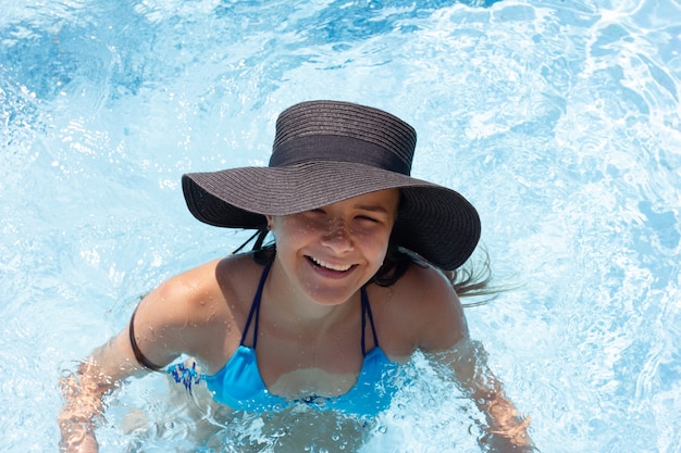 Young beautiful girl in a hat in the pool, top view