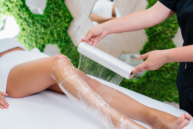 A young beautiful girl is doing a cosmetology procedure full body wrap in a modern beauty salon. Spa procedures in a beauty salon.