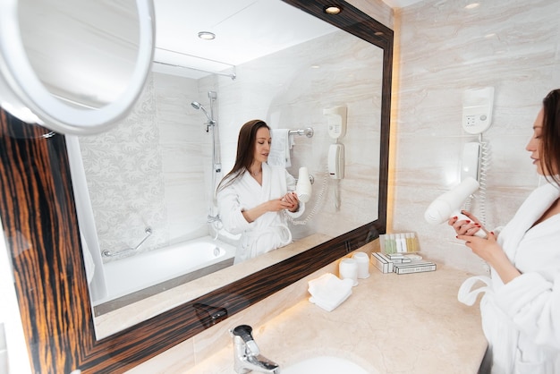 A young beautiful girl is drying her hair in a beautiful white bathroom A fresh good morning at the hotel Rest and travel Hotel recreation and tourism