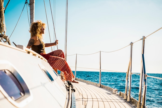 Young beautiful girl lay down and relax on a sail boat enjoying silence and nature