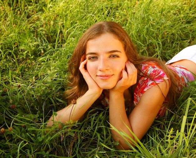 Young beautiful girl lays on a grass