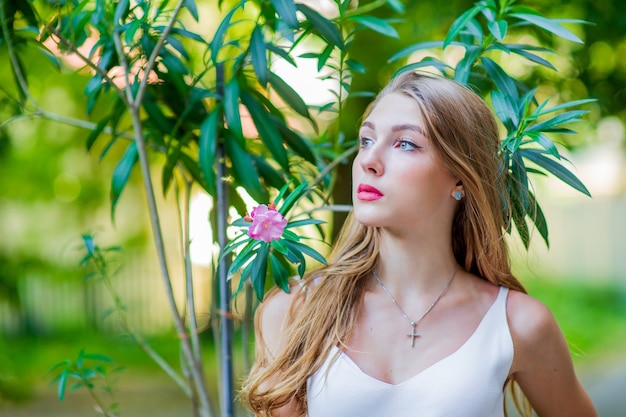 Young beautiful girl posing outdoor, wearing fashionable white dress. Summer style.