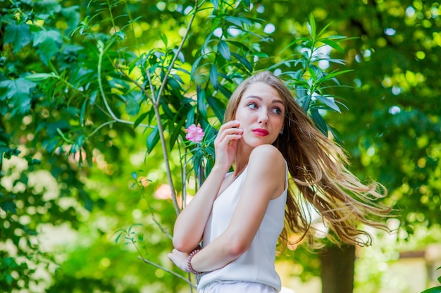 Young beautiful girl posing outdoor, wearing fashionable white dress. Summer style.