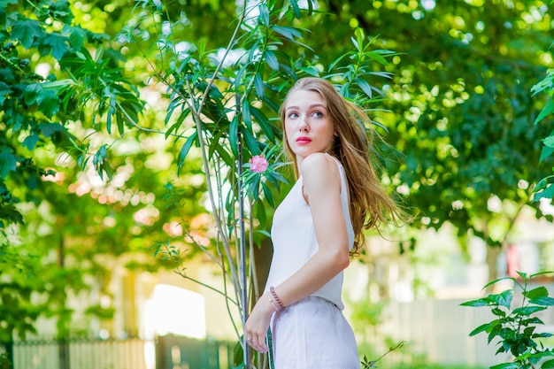 Young beautiful girl posing outdoor, wearing fashionable white dress. Summer style.