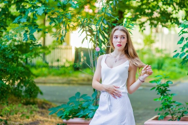 Young beautiful girl posing outdoor, wearing fashionable white dress. Summer style.