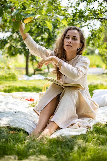 Young beautiful girl reading paper book in the garden