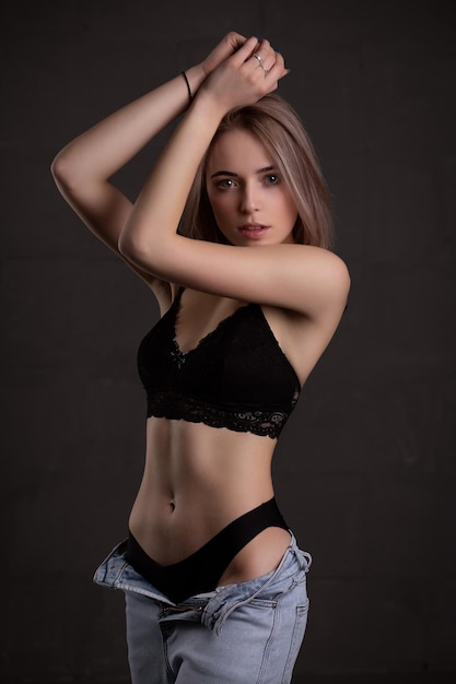 Young beautiful girl in sexy black underwear on a dark background