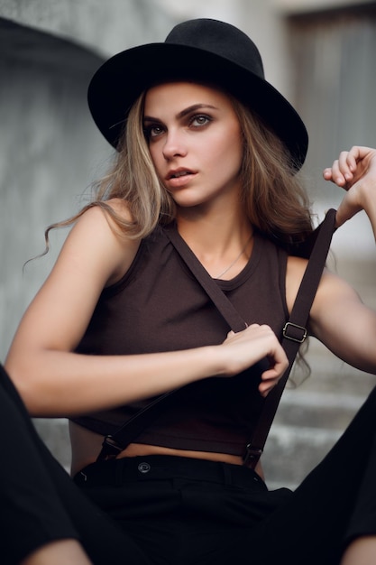 Young beautiful girl in a short elegant top and black hat